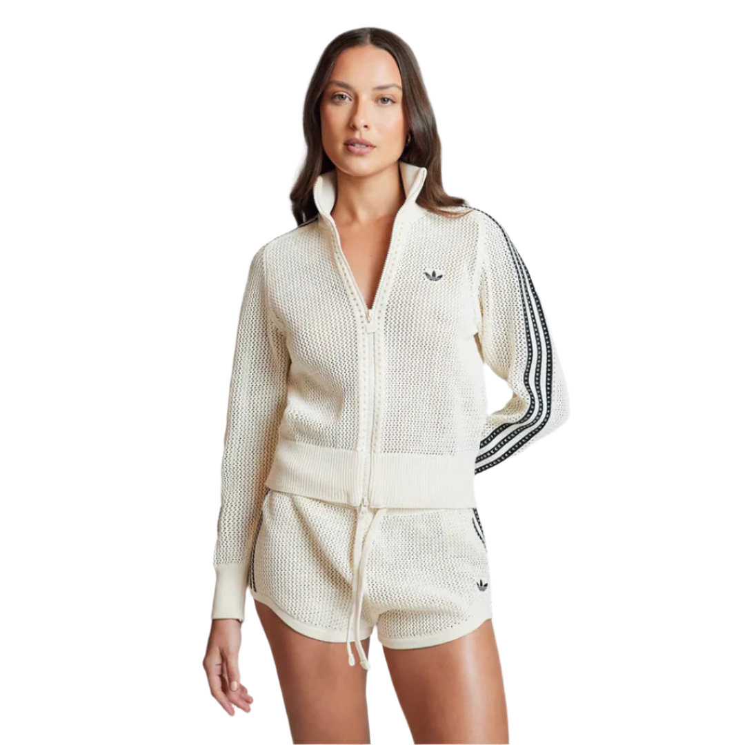 Woman wearing a cream-colored Adidas tracksuit on a light gray background