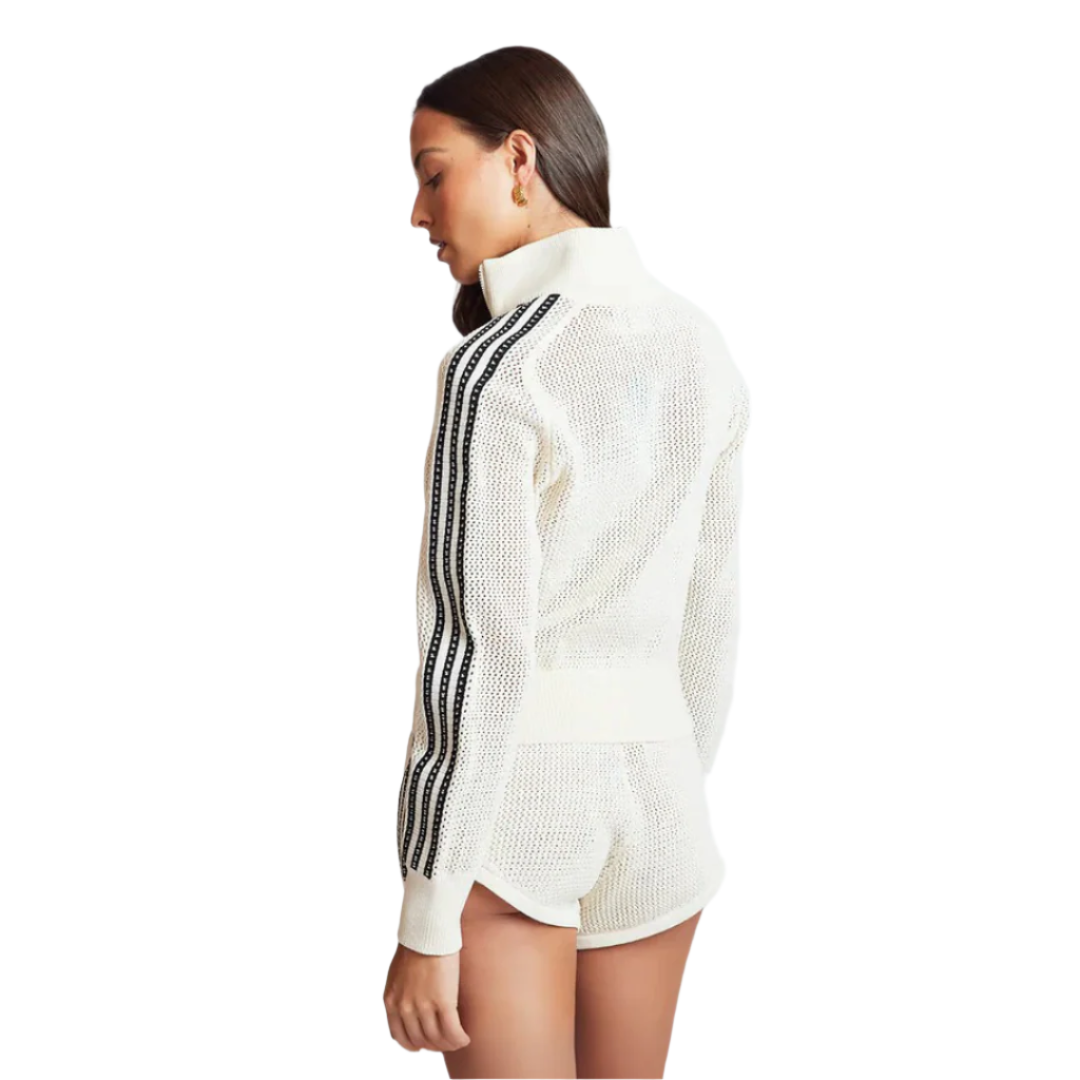 Woman wearing a white outfit with black stripes on a light gray background